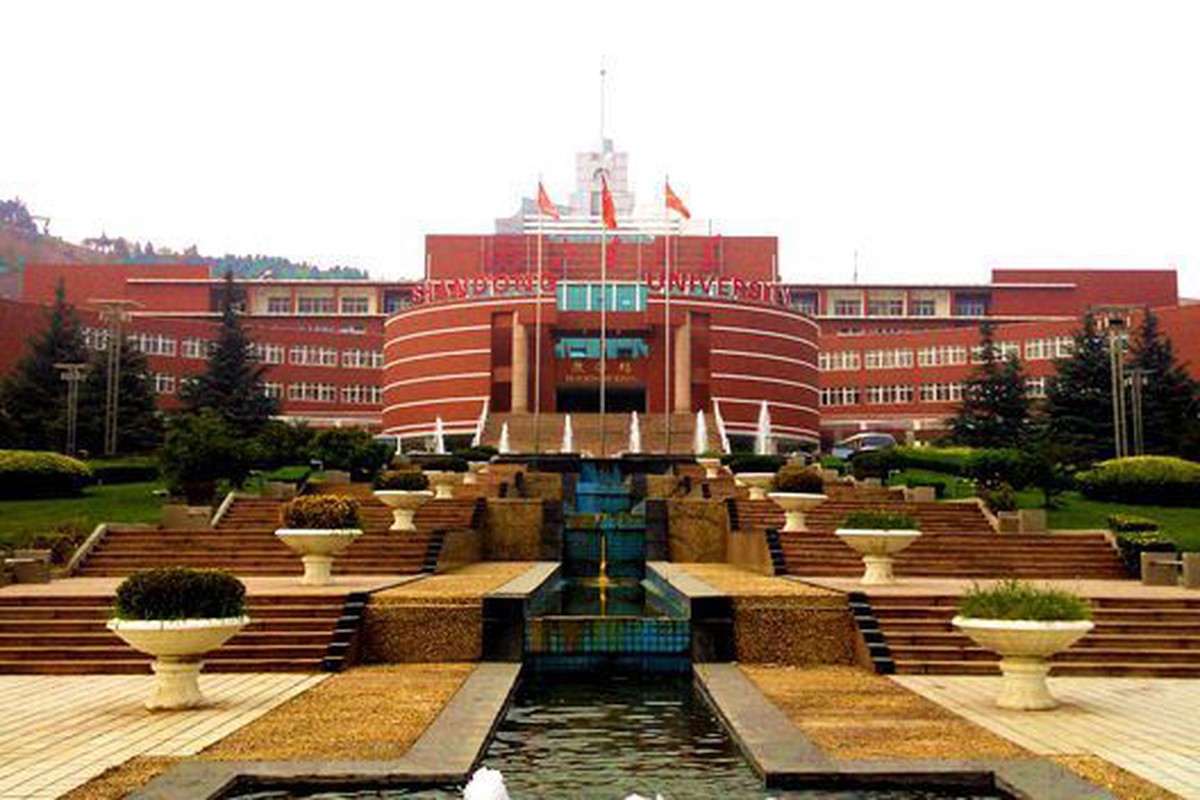 A red academic building facing a broad open plaza.