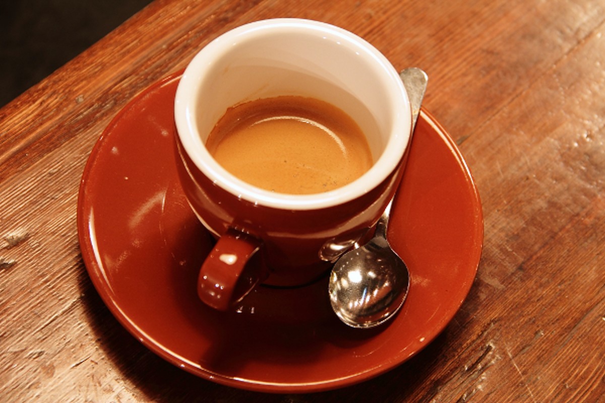 A cup of coffee on a rustic wooden table.