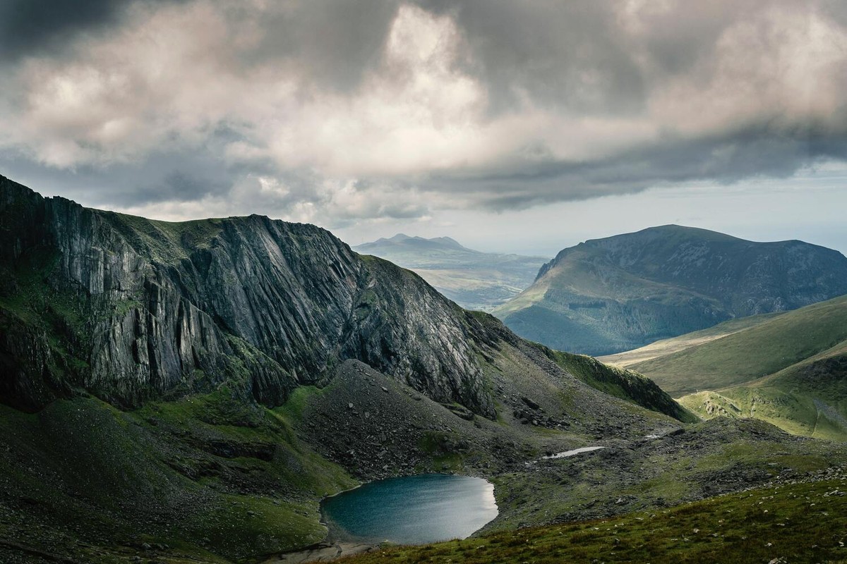 A mountain valley and lake beneath dramatic clouds.